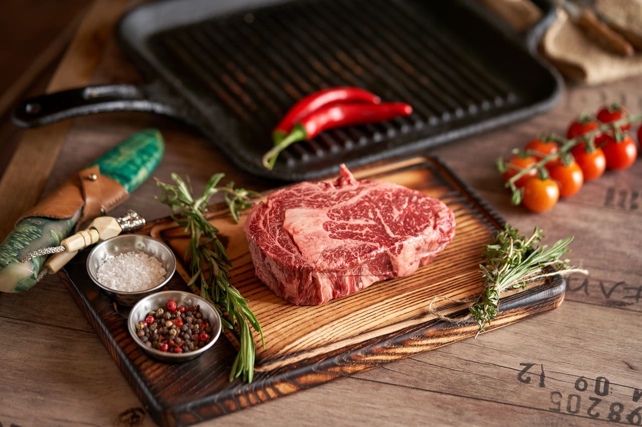 Fresh-juicy-ribeye-steak-on-a-cutting-board-with-sprigs-of-rosemary