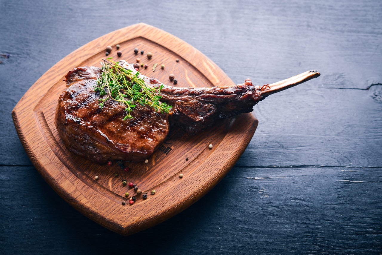 Steak-on-the-bone.-Top-view.-Free-space-for-text.-On-a-wooden-background